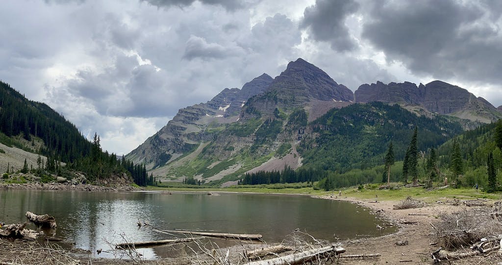 Looking back at Maroon and North Maroon from Crater Lake with storm clouds fully formed above them.